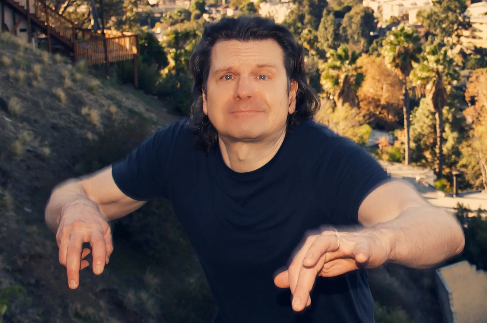 Mike Grebb playing air piano on a hillside above Los Angeles, color