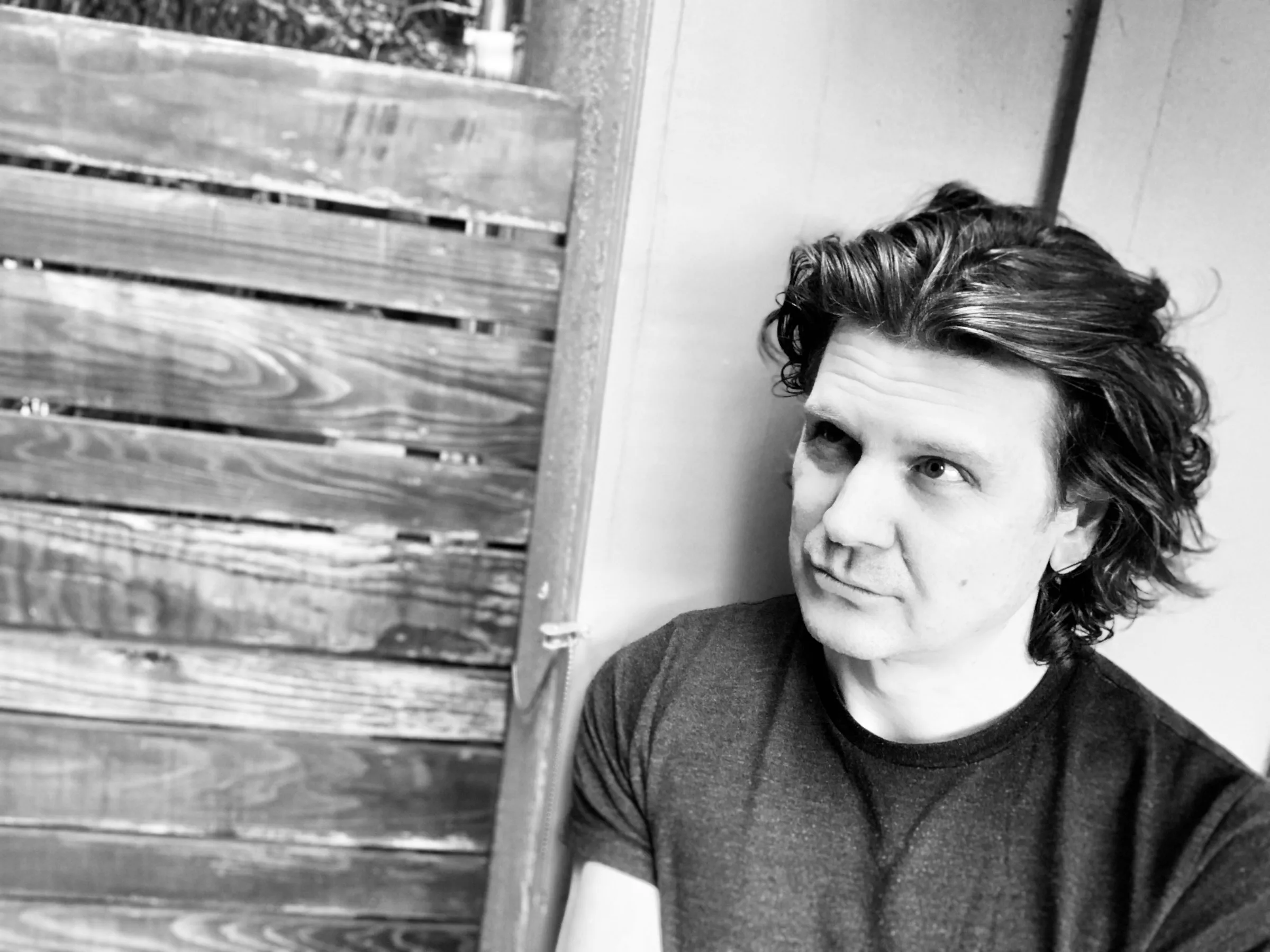 Mike Grebb leaning against a wooden fence, black and white