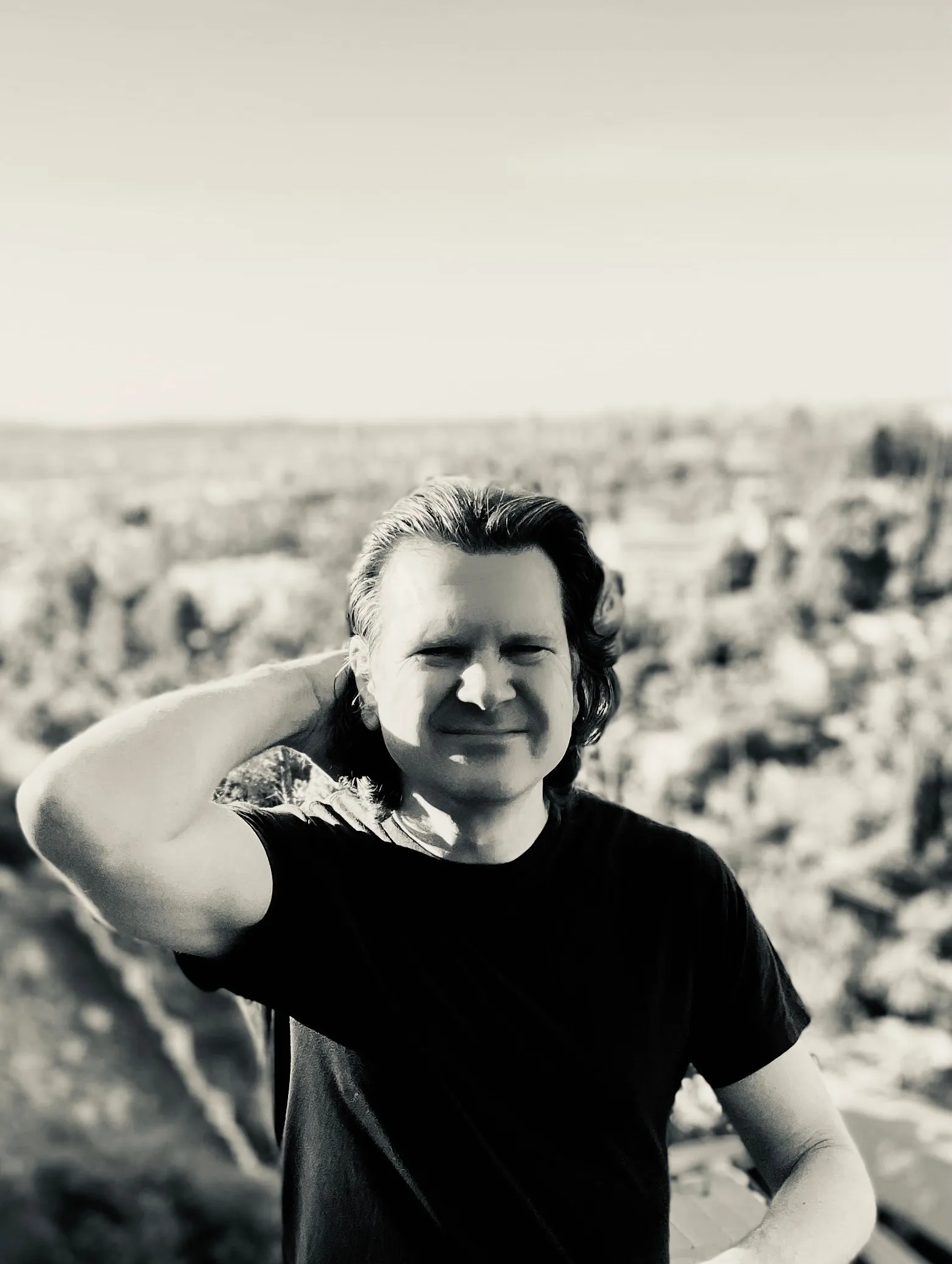 Mike Grebb on a hillside above Los Angeles, one hand behind his head, black and white