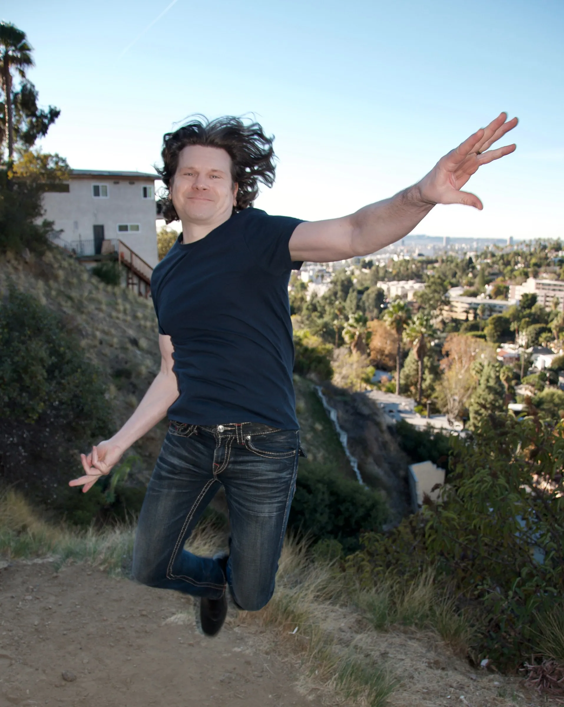Mike Grebb jumping on a hillside above Los Angeles, color