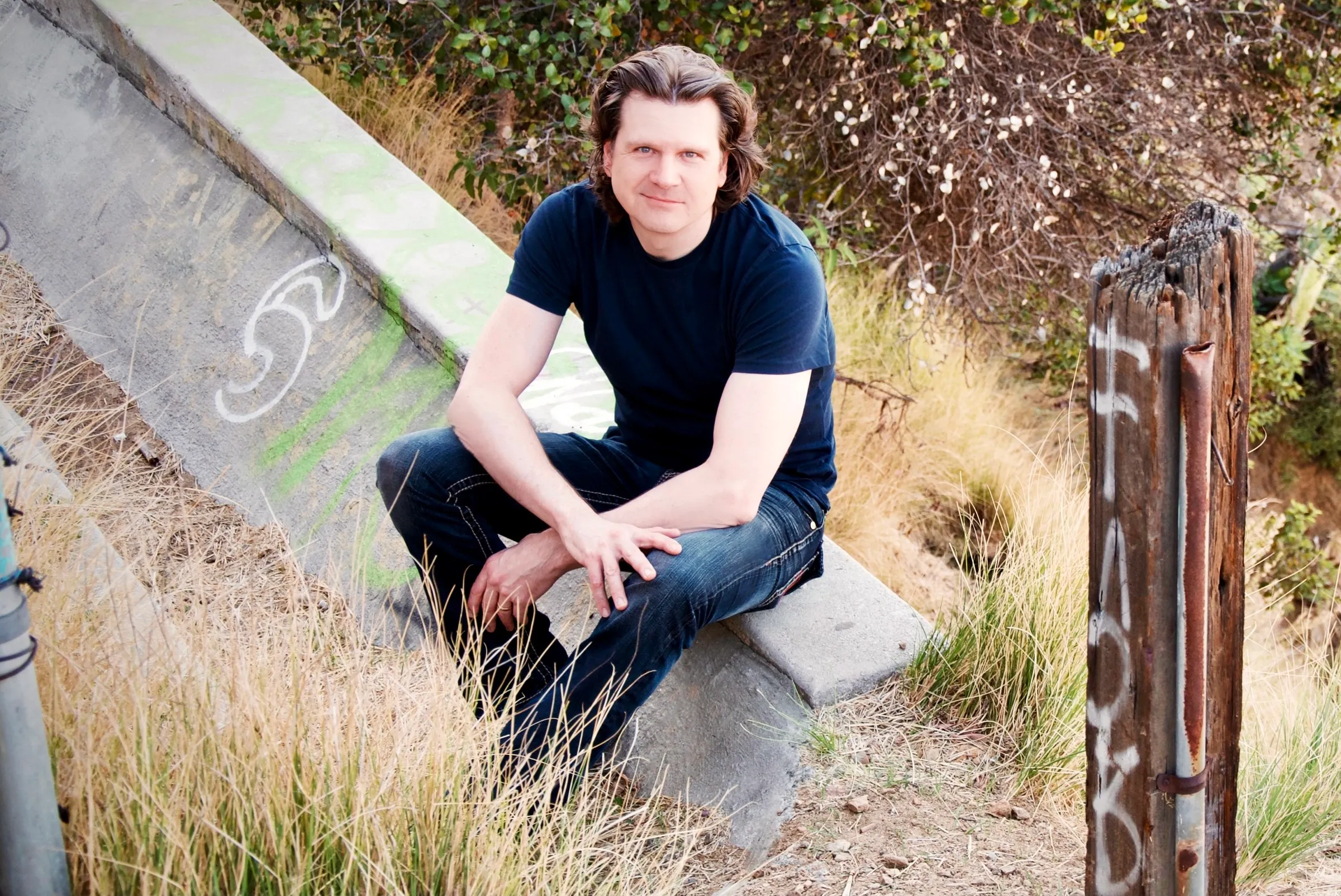 Mike Grebb sitting on a concrete ledge on a Los Angeles hillside, color